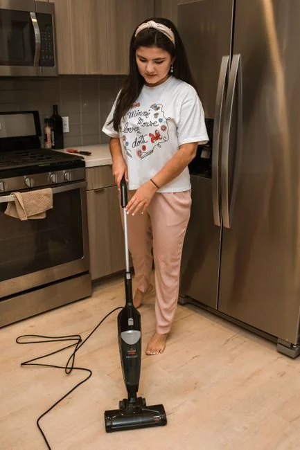 Close-up of a vacuum cleaner on a patterned carpet in a sunlit room, capturing a moment of household cleaning.